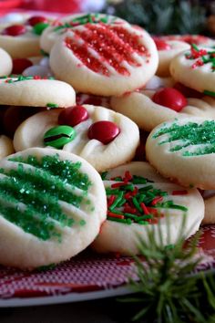 christmas cookies decorated with green and red sprinkles on a plate next to a pine tree