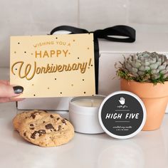 a person holding a happy valentine's day card next to cookies and a potted plant