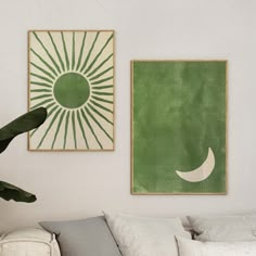 two green and white paintings hang on the wall next to a couch in a living room