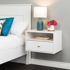 a white bed sitting next to a night stand with a lamp on top of it