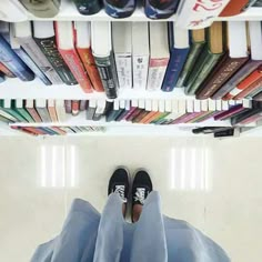 a person standing in front of a bookshelf with their feet on the floor