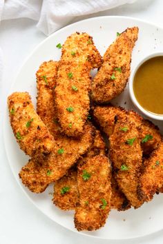 fried chicken sticks on a plate with dipping sauce and parsley green garnish