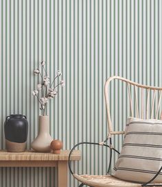 a chair and vases on a table in front of a green striped wallpaper