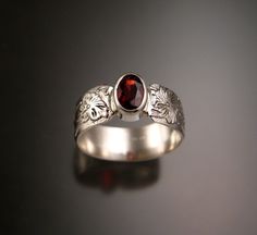 "This beautiful Garnet is a rich Raspberry red color. Measures 7x7mm and weighs about 1ct. Bezel-set stone with 7mm wide and 1mm thick Victorian Floral pattern band. Size 8 ring is pictured (for your scale reference). Specify your ring size in a \"note to seller\" at check out." Wedding Garnet Cabochon Jewelry, Ruby Oval Cabochon Wedding Jewelry, Oval Cabochon Ruby Wedding Jewelry, Wedding Ruby Oval Cabochon Jewelry, Sterling Silver Cabochon Ruby Ring For Wedding, Oval Cabochon Garnet Jewelry For Anniversary, Anniversary Garnet Oval Cabochon Jewelry, Red Oval Cabochon Jewelry For Wedding, Oval Ruby Jewelry With Engraving