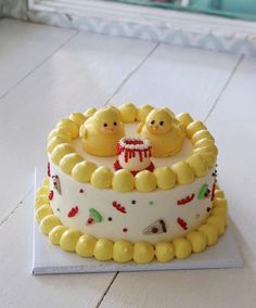 there is a cake with yellow frosting and two little chicks on top of it