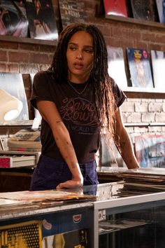 a woman standing in front of a table with books on it and looking at the camera