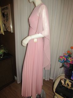 "1960's lovely dress with empire waist, sleeveless, back nylon zipper, pleated skirt, polyester fabric, v-neckline, large pink flower applique across bust, and an attached draping shawl/top that makes it a unique dress. Store tags are still attached from the May Co. Dept. store from back in the 60's, with a size 7/8 tag. Dress is old dead-stock, with Pointy Bust 32\", Armholes 16\", Waist about 26\". Dress is in excellent condition. PRICE IS $89.00SALE FINAL/AS IS/NO RETURNS." Pink Fitted Dress With Accordion Pleats, Fitted Pink Dress With Accordion Pleats, Shawl Top, Donna Mills, Unique Dress, Dress Store, Flower Applique, Unique Dresses, Lovely Dresses