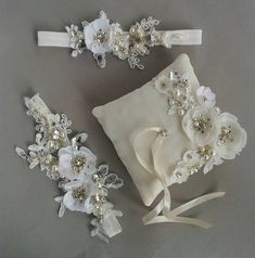 two wedding garters and a ring pillow on a gray surface with white ribbons