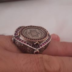 a person's hand holding a silver ring with an inverted design and ruba dots