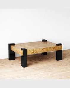 a coffee table with two black legs and a wooden top on a hard wood floor