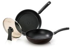 an assortment of cooking pans and pots on a white surface with one frying pan in the foreground