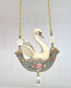 a white swan is hanging from a gold chain