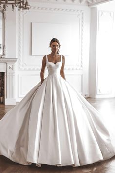 a woman in a white wedding dress standing on the floor with her hand on her hip