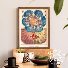 an art print hangs on the wall above a wooden table with cups and saucers