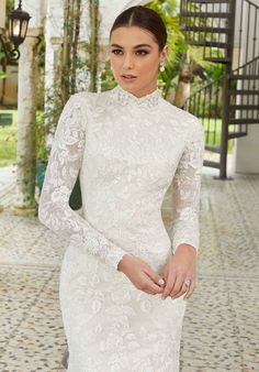 a woman in a white dress standing on a brick floor with her hand on her hip