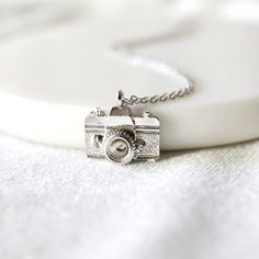 "Beautiful and lovely camera necklace made of silver plated camera pendant with skinny rhodium plated brass chain. Simple and cute looking dainty necklace is good for yourself or gift ! Your necklace will ship in a gift box. ♥Chain length 15\"-20\" ♥Pendent 1/2\" 5/8\" ♥Rhodium plated over brass ♥ Delivery Time Fast shipping within 1 - 3 days ♥ See more Rudiana Accessories Rudiana.etsy.com" Pretzel Necklace, Camera Necklace, Bridesmaid Necklace Gift, Prom Necklaces, Fancy Jewellery, Jewelry Stand, Necklace Dainty, Brass Chain, Dainty Necklace