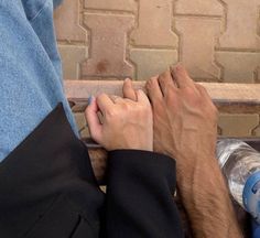 two people are sitting on a bench with their hands touching each other's fingers