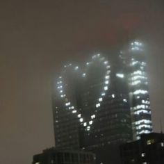 two tall buildings are lit up in the fog