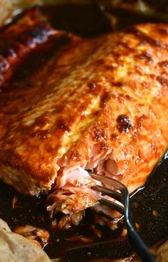 a piece of meat is being cooked in a skillet with a fork and knife