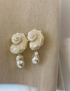 This is a pair of handcrafted white conch shell earrings with pearl pendants, crafted from natural conch shells and featuring s925 silver studs. The design is unique and exquisite, making them a perfect and special gift. Material - Conch, Pearl, s925 Silver - Free shipping. - Handcrafted, packaged in an exquisitely designed gift box, perfect for gifting. - Order processing time: 3-7days. Shell-shaped Pearl Earrings With Pearl Charm, Sterling Silver Shell As Gift, Unique White Pearl Earrings For Wedding, Elegant Shell Dangle Earrings, Pearl Shell Earrings With Pearl Charm, Pearl Drop Shell As A Gift, Elegant Dangle Shell Earrings, Unique Silver Shell Earrings, Elegant Dangle Shell