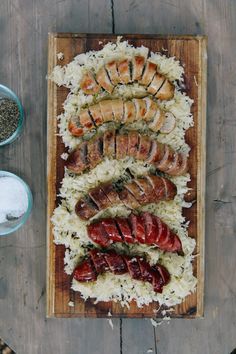 an overhead view of meats and rice on a wooden platter next to two bowls