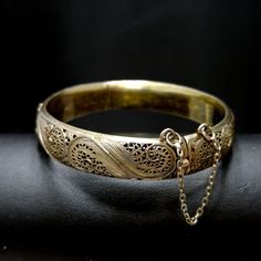 *Description: This is a beautiful Art Nouveau hinged silver bracelet with a gold wash from around the 1920s. It has European origins with stamps for silver and one difficult to read on the clasp. Photo is included. This silver bracelet with a gold wash was tested by me and tested for silver and minimum 10K gold wash or vermeil. The clasp and hinge are in great working order. If you are looking for a wonderful heirloom gift, this would be perfect. This bracelet would be a great addition to your v Classic Ceremonial Bracelet With Intricate Design, Gold Brass Bangle Bracelet For Formal Occasions, Elegant Antique Gold Brass Bracelet, Gold Collectible Bracelet, Elegant Antique Gold Bangle Bracelet, Antique Gold Bangle For Formal Occasions, Antique Gold Bangle Jewelry For Formal Occasions, Formal Yellow Gold Brass Bracelets, Antique Gold Engraved Bracelet