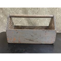 an old wooden box sitting on top of a black table next to a zebra print wall