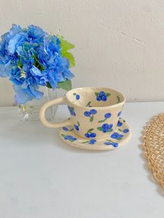 a blue flowered cup and saucer next to a straw hat on a table