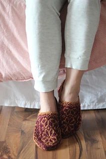 a woman's feet wearing slippers on top of a bed