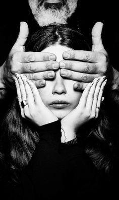 a woman covering her eyes with hands while standing next to a man's head