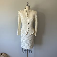 A lovely cream colored two piece 80s suit in great condition! Has two discoloration marks. One on skirt and one on back of shoulder. See I'm ages. The blouse closes with buttons down the front and ties tighter at the back of waist. A zipper runs down the back of the skirt.  Size: S/M Tag - Savannah Era - 80s  Material - cotton, acetate, polyester, plastic buttons, nylon zipper, chiffon Blouse: Bust -  Waist -  Arm length -  Length -  Skirt: Waist -  Hips -  Length -  Washing - lightly steam clea Fitted White Silk Sets, White Fitted Silk Sets, Fitted Off White Silk Set, Fitted Silk Sets In Off White, Elegant Off White Sets For Spring, Elegant Beige Fitted Skirt Suit, Elegant White Skirt Suit For Wedding, Formal Beige Silk Sets, Fitted Vintage White Sets