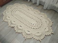 a crocheted doily is laying on the floor in front of a bed