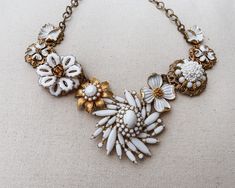 Rochelle statement necklace is made of repurposed vintage jewelry. White enamel and gold filigree flowers and sunbursts make this assemblage bib necklace super versatile and fun. Necklace is adjustable from 16-19 inches with hook clasp. ~An enchantingly unique design from Jewelry by Chyrise Vintage White Necklaces, White Vintage Necklace, White Vintage Necklaces For Vintage Events, White Vintage Necklace With Charm, Vintage White Necklaces With Jewels, Victorian White Jewelry For Vintage Events, White Vintage Jewelry, White Vintage Jewelry For Vintage Events, Vintage White Necklace With Intricate Design