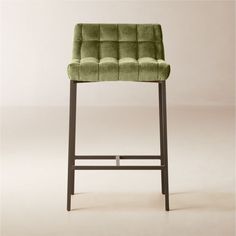 a green velvet bar stool with metal frame and footrests on an off - white background