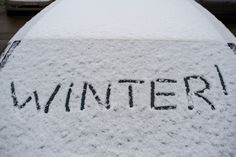 the word winter written in black ink on top of a snow covered car's hood