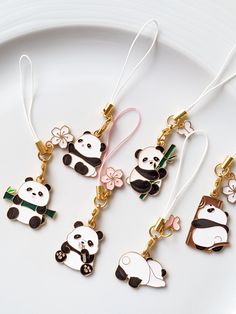 four panda key chains on a plate with flowers and ribbons hanging from the end of them