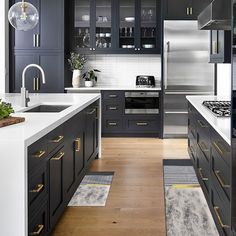 a kitchen with black cabinets and white counter tops, gold trimming on the doors