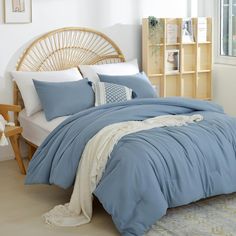 a bed with blue comforters and pillows in a room next to a book shelf