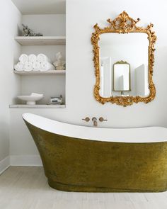 a bath tub sitting under a mirror in a bathroom