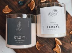 two candles sitting next to each other on top of a wooden table with dried flowers