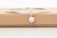 Beautiful handmade hammered sterling silver bangle with a stunning grey baroque fresh water pearl. The bracelet is 65mm in circumference and the pearl measures between 8mm.  Simple yet striking this is great of everyday wear. The bangle makes a lovely birthday gift and a great present for a bridesmaid to remember your special day by. This elegant bracelet will come beautifully packaged in a gift box with ribbon. The perfect gift or simply treat yourself. Please visit my shop to see my full range of bangles. https://www.etsy.com/shop/Joonthemoon1?ref=si_shop Elegant Sterling Silver Hammered Bangle, Elegant Hammered Sterling Silver Bangle Bracelet, Elegant Hammered Sterling Silver Bangle, Minimalist Silver Hammered Bangle, Minimalist Hammered Silver Bangle, Silver Bangle Bracelets For Bridesmaid Gift, Hammered Sterling Silver Bangle Bracelet Gift, Minimalist Hammered Bangle As Gift, Sterling Silver Hammered Bangle As Gift