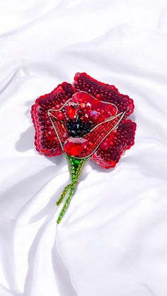 a red rose made out of beads on a white sheet