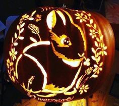 a carved pumpkin with an image of a rabbit on it's face and leaves