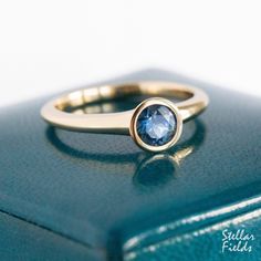 Minimal and modern, this bezel engagement ring features a natural, 5mm Montana sapphire set in a round tapering round bezel. Adhering to its modern and minimal character, the tapered bezel setting merges seamlessly into the ring's shank. The width of the band measures between 2.25mm to 3mm wide along its length, while its cross sectional thickness measures about 2.3mm along the bottom and sides. The height from the stone's table to the top of finger measures about 4mm to ensure a low and sleek profile, while the inner band is of 'comfort fit' design thus making this ring very comfortable for everyday wear.  The ring shown in the picture has a polished mirror finish but I'll be happy to provide a brushed matte finish upon request. All jewelry is designed and hand made by me in my studio her 14k Gold Sapphire Ring With Tension Setting, Modern Sapphire Ring With Tension Setting And Round Band, Modern Yellow Gold Sapphire Ring With Bezel Setting, Elegant Sapphire Ring With Smooth Bezel As Gift, Modern Sapphire Ring With Bezel Setting For Anniversary, Modern Round Birthstone Ring With Tension Setting, Modern Round Sapphire Promise Ring, Modern Solitaire Sapphire Ring With Round Band, Sapphire Ring With Smooth Bezel For Wedding