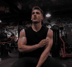 a man sitting on top of a bench next to a gym equipment rack in a dark room