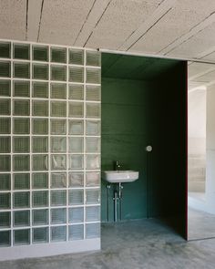 an empty bathroom with a sink and mirror in it's corner, next to a wall made out of glass blocks