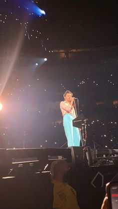 a woman standing on top of a stage next to a microphone in front of a crowd