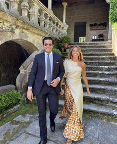 a man and woman in formal wear walking down some steps with an old building behind them