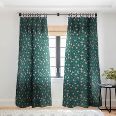 a bedroom with green curtains and a white rug on the floor next to a window