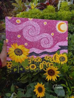 someone holding up a painting with sunflowers in the foreground